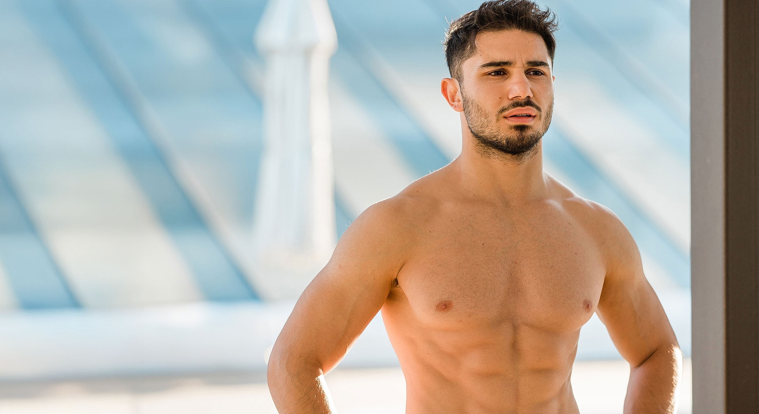 Man standing shirtless in natural light.