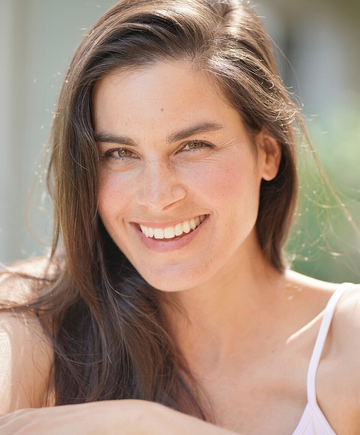 Smiling woman with long hair outdoors.