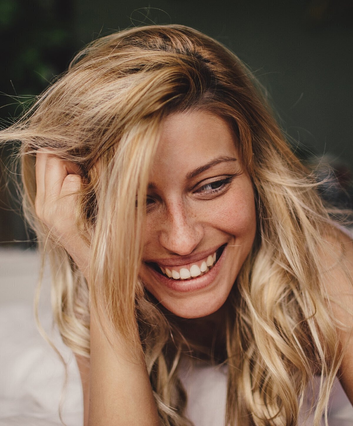 Smiling woman with wavy blonde hair indoors.