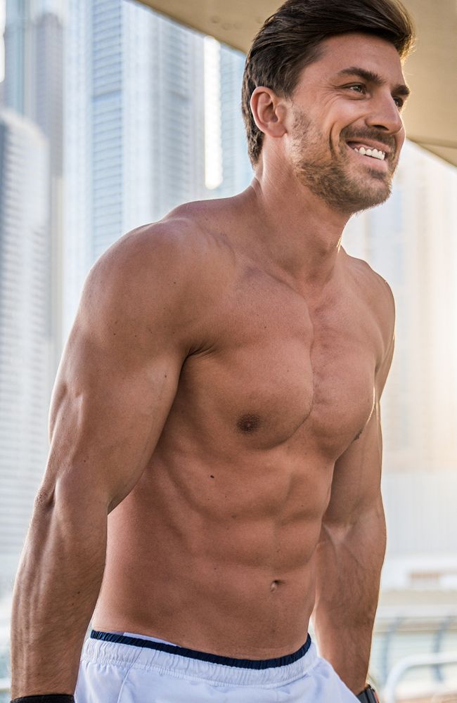 Fit man smiling outdoors with urban background.