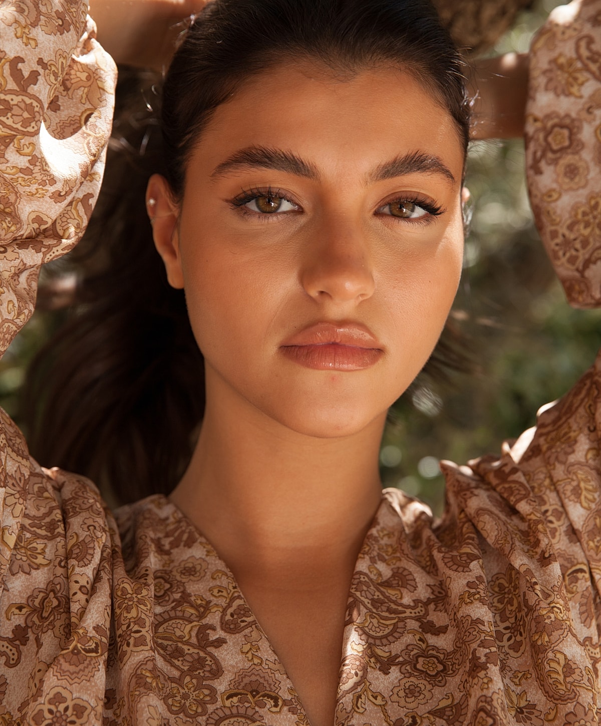 Woman with brown hair in patterned blouse.