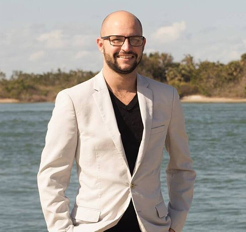 Man in white suit by the water.
