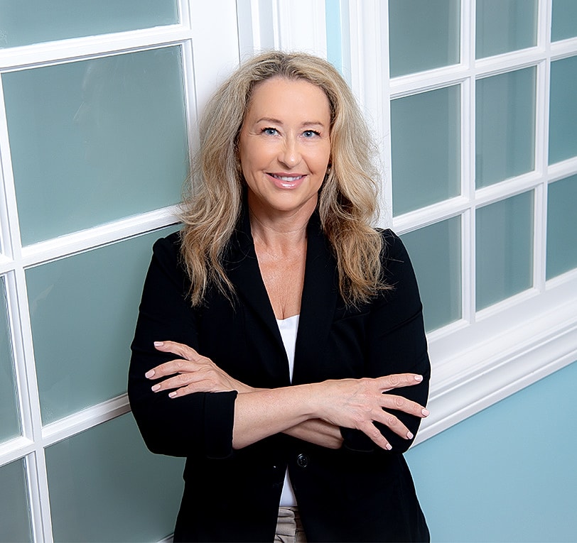 Professional woman smiling with crossed arms.
