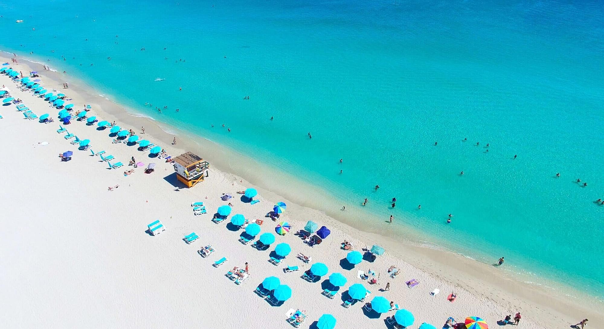 Aerial view of beach with umbrellas and people.