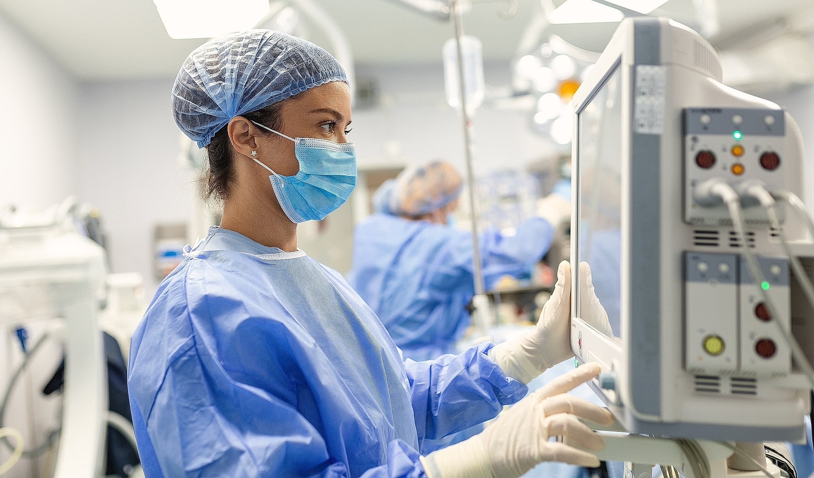 Healthcare professional monitoring patient equipment in surgery.