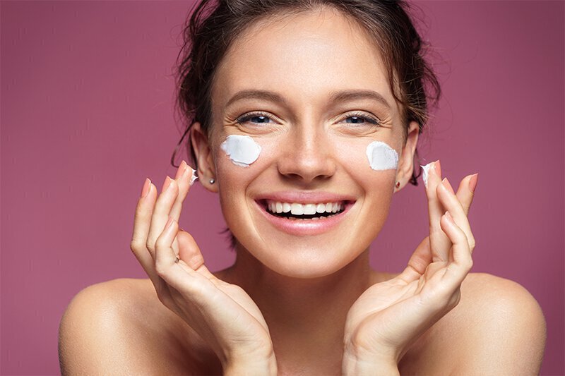 Woman putting cream on face